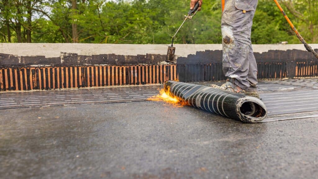 Workers in the construction of a roof, flat roof repair, flat roof replacement, roofers working on flat roofing project