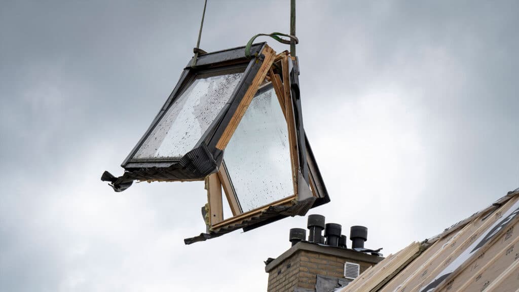 Old skylight being removed, a skylight suspended in the air after being detached from the roof